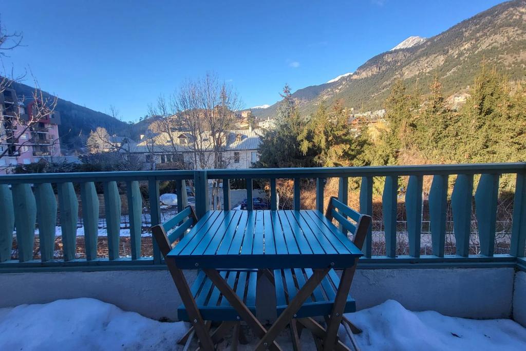 - une table de pique-nique bleue sur un balcon avec des montagnes enneigées dans l'établissement 6-bed apartment at the foot of the slopes, à Briançon
