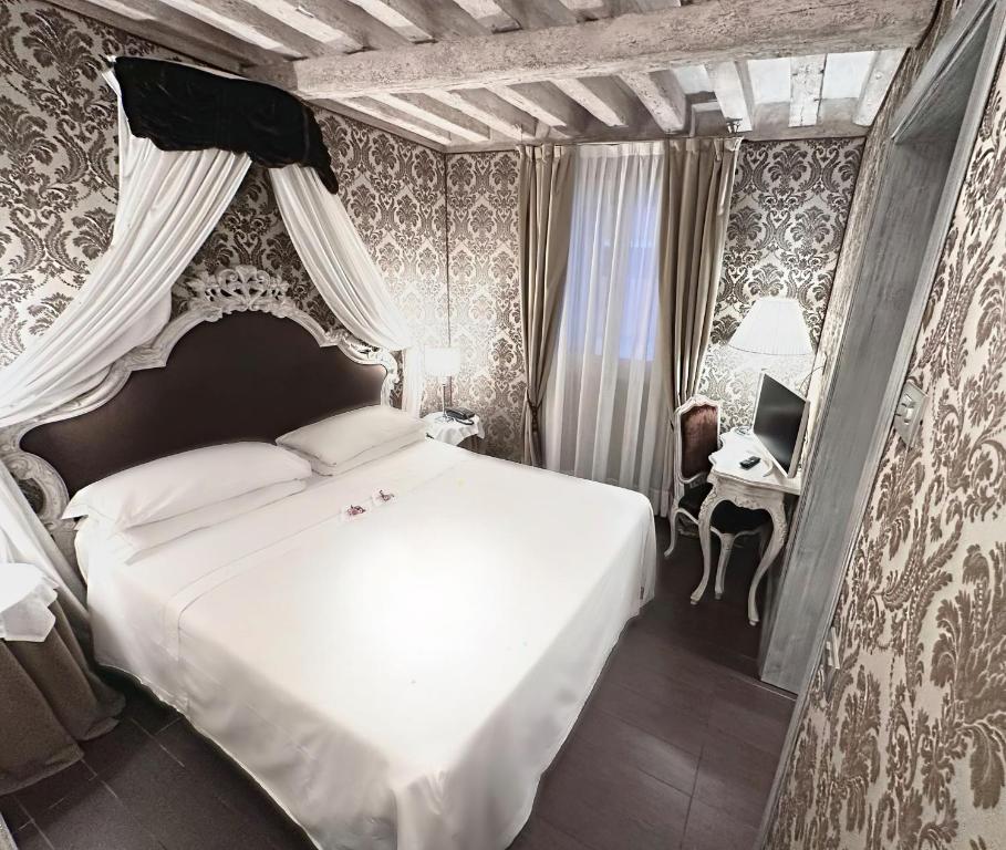 a bedroom with a white bed and a desk at Hotel Antiche Figure in Venice