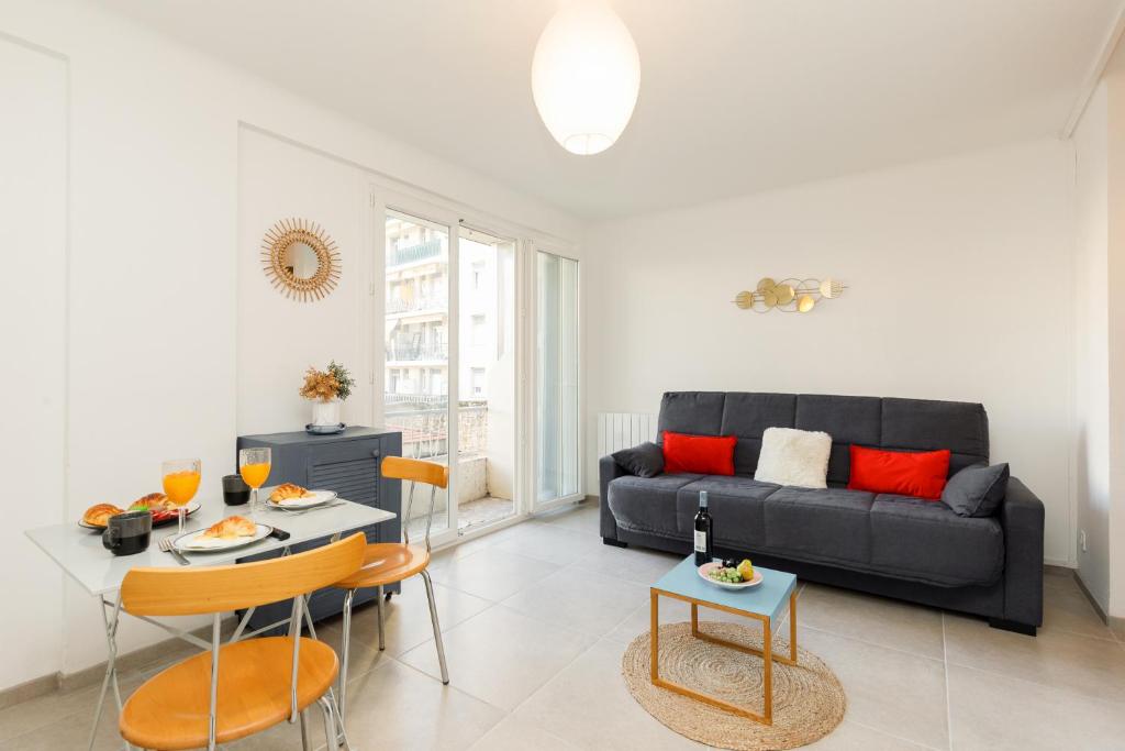 un salon avec un canapé noir et une table dans l'établissement Le Lido YourHostHelper, à Cannes