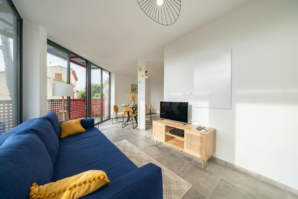un salon avec un canapé bleu et une télévision dans l'établissement Renovated apartment with balcony and parking, à Saint-Raphaël