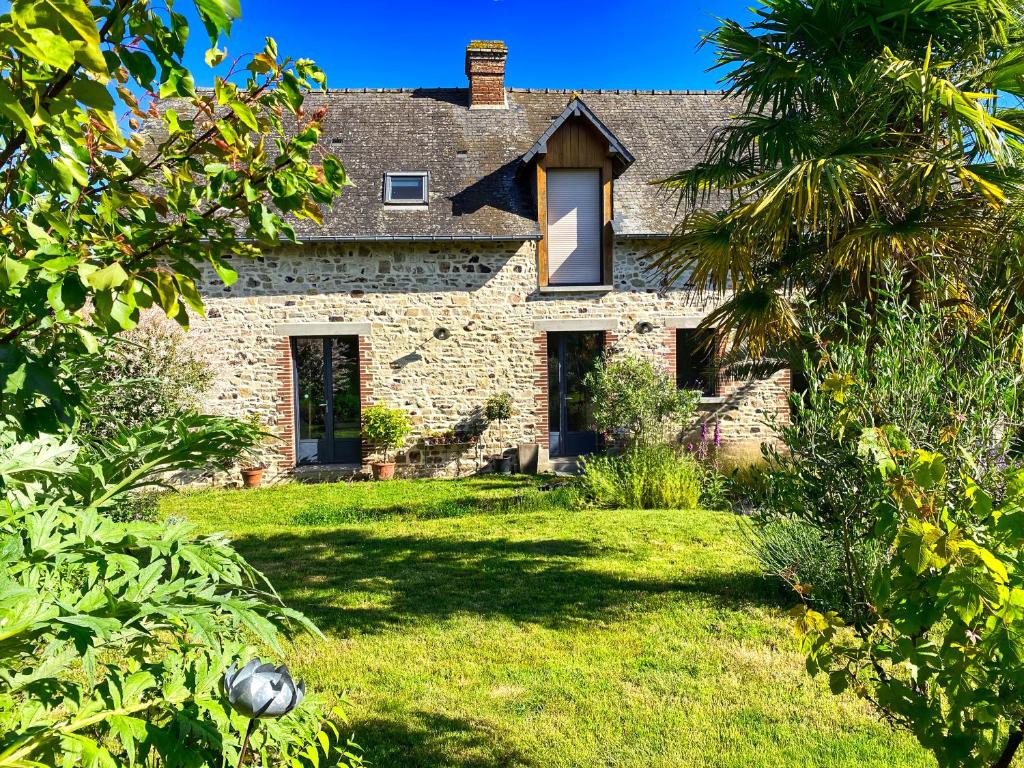 une ancienne maison en pierre avec un palmier dans l'établissement Le Chêne Loret, à Poligné