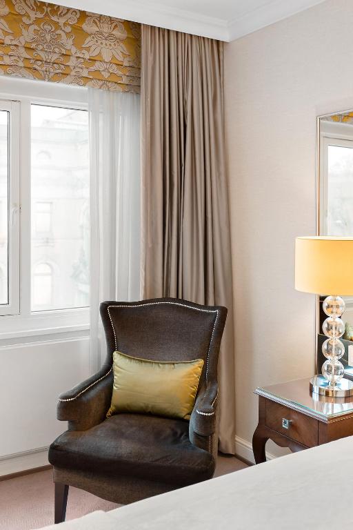 a chair with a yellow pillow in a hotel room at Hotel Continental in Oslo