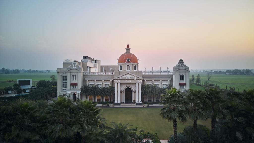 a large white house with a red roof at Royal Kingdom Sarovar Portico Pilibhit in Pīlībhīt