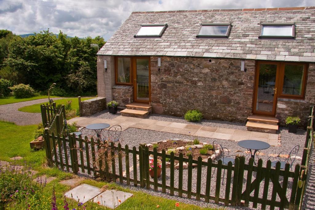 a stone house with a fence and a patio at Ghyll Farm B & B in Lamplugh