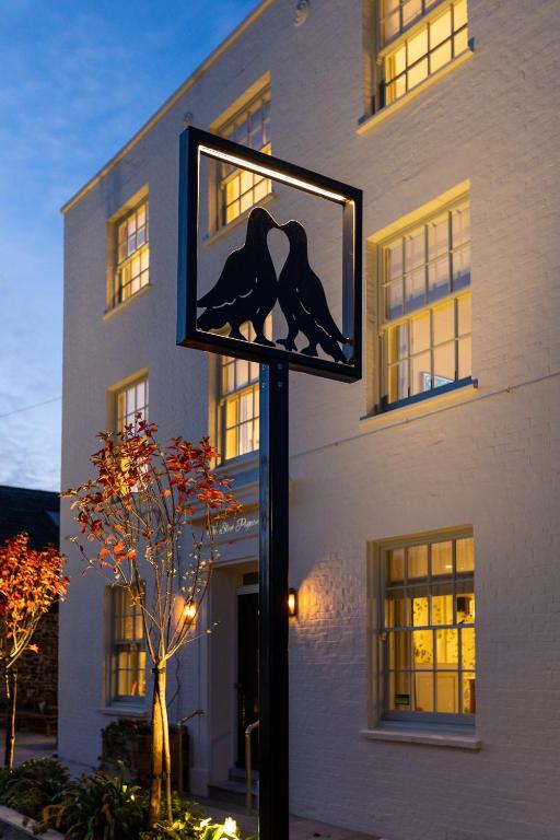 a street light with two birds on it in front of a building at The Blue Pigeons Hotel and Restaurant in Worth