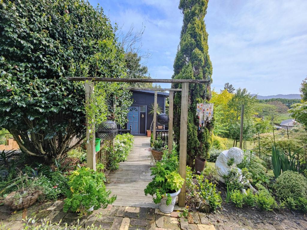 a wooden walkway in a garden with a blue door at starry nights tree house in Waikino