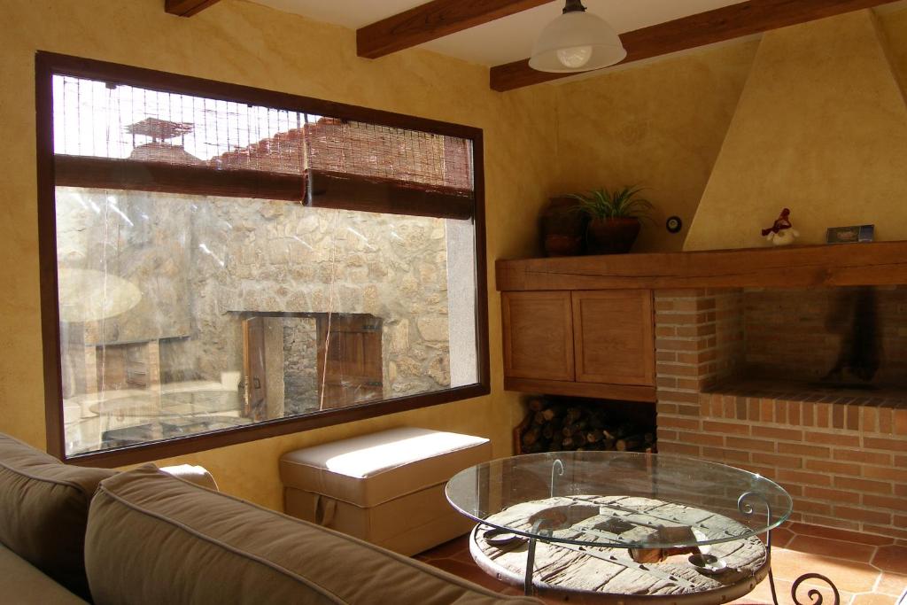 a living room with a glass table and a fireplace at Casa Rural El Zahorí De Pinedas in Pinedas