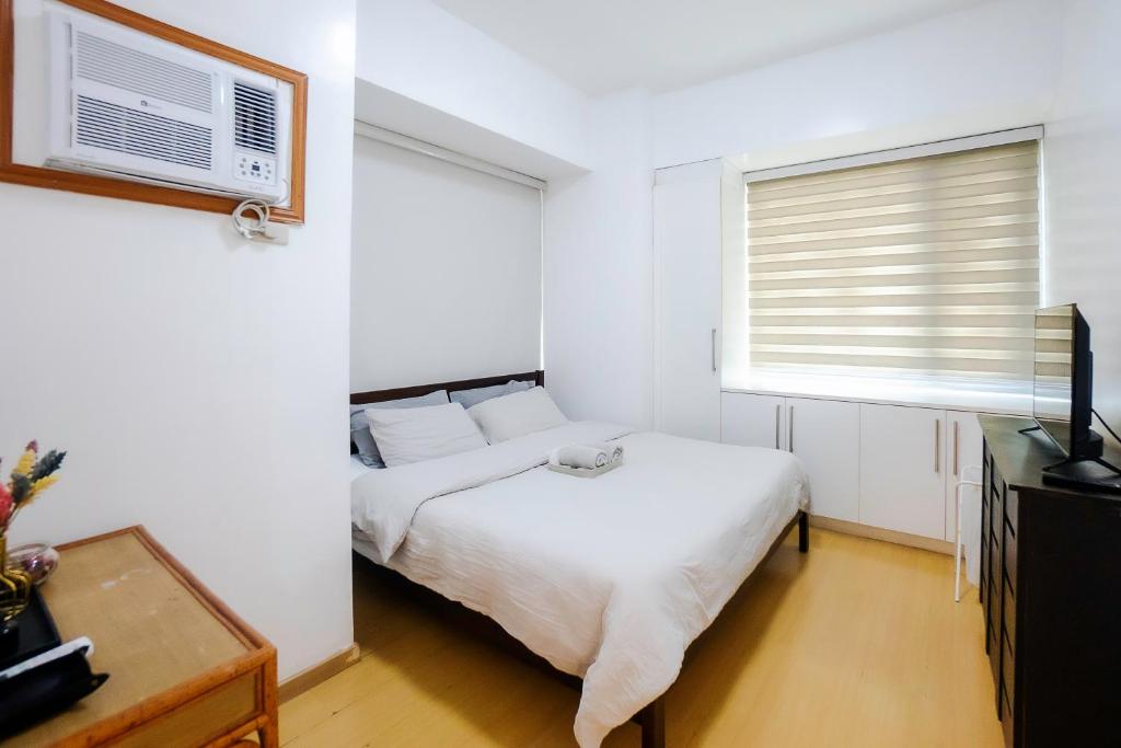a white bedroom with a bed and a window at Premium 1BR unit at The Avant in Manila