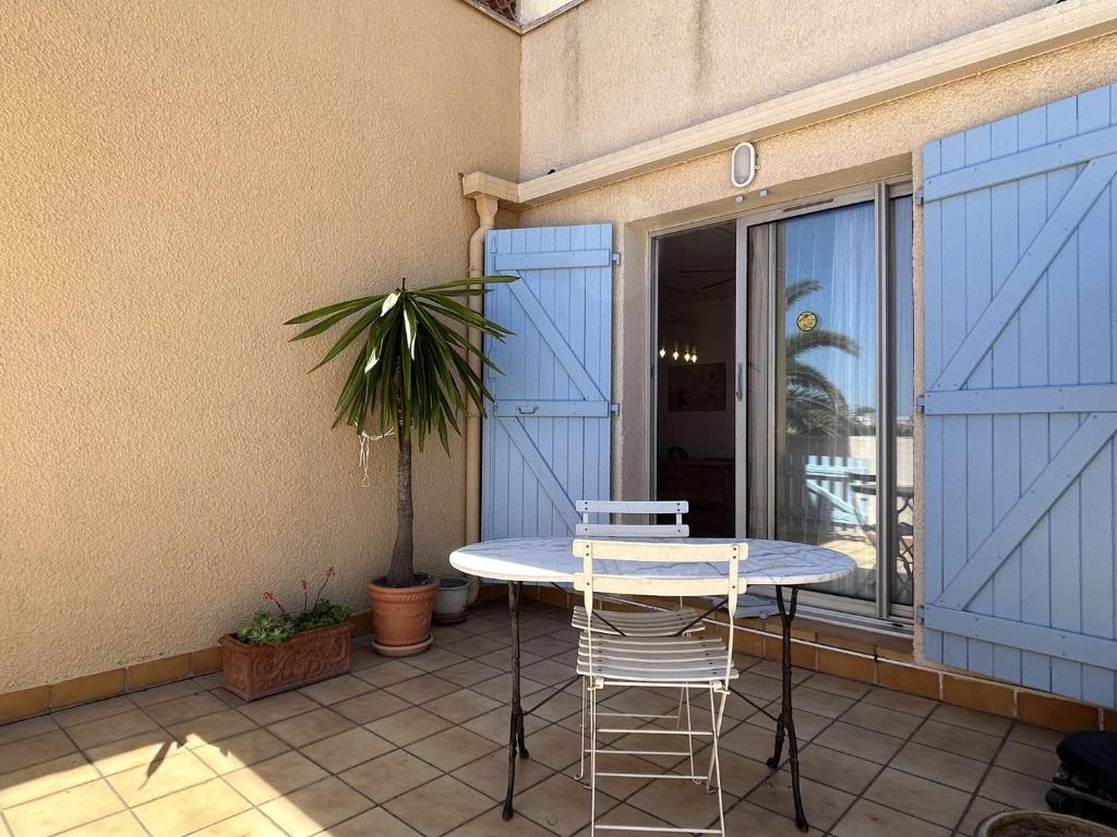 d'une table et de chaises sur un balcon avec portes bleues. dans l'établissement Appart studio 2 couchages BANYULS SUR MER BN030-E02, à Banyuls-sur-Mer