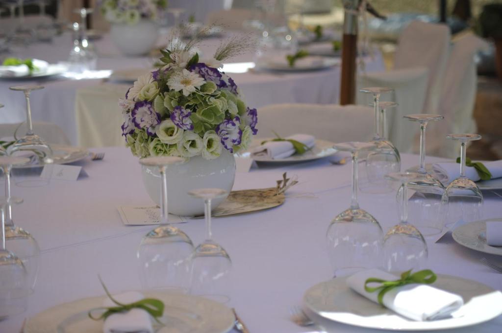 a table with wine glasses and a vase of flowers at Masseria Valente in Ostuni
