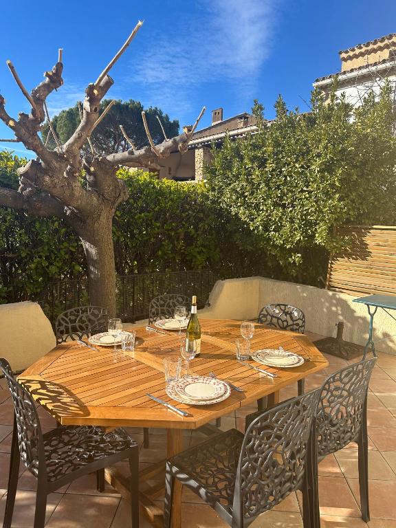 - une table en bois avec des chaises et une bouteille de vin dans l'établissement Maison Parc du Verdon - Clim & Terrasse ombragée, aux Salles-sur-Verdon