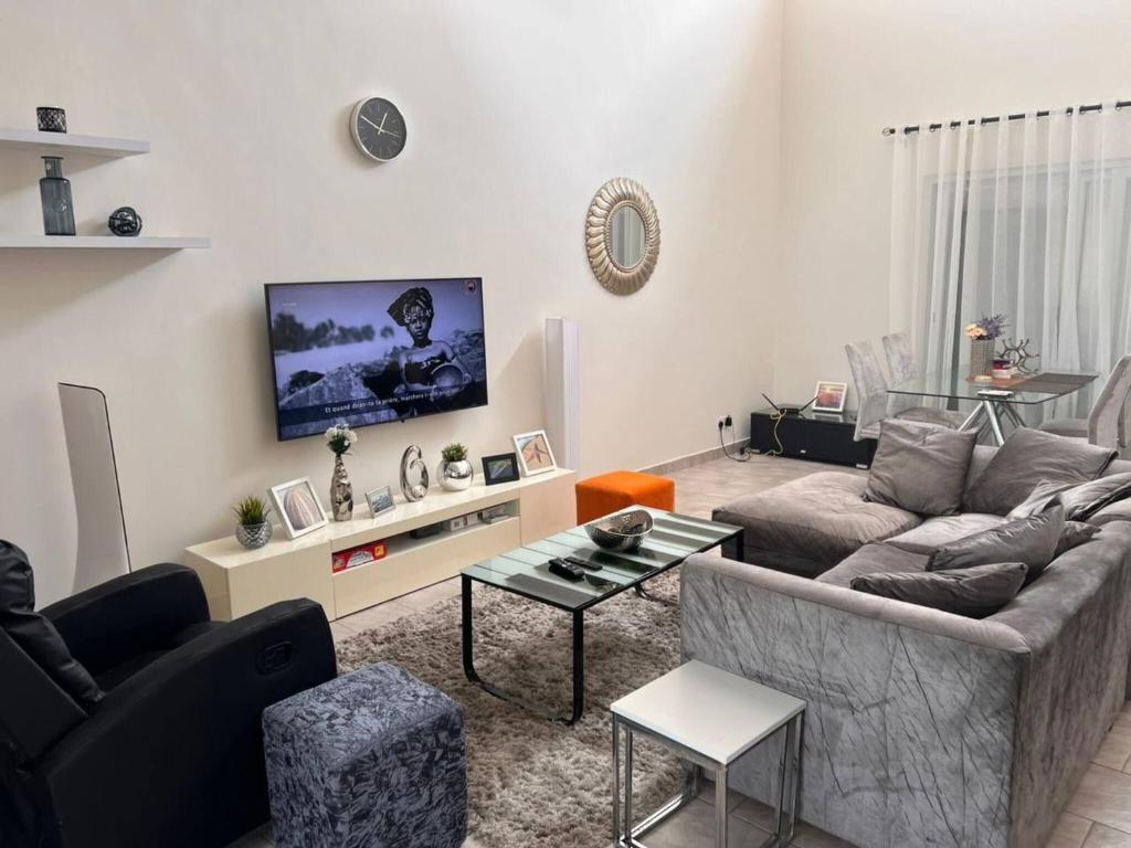 un soggiorno con un divano e una TV di Serene Oasis in East Legon Hills - Chic 2 Bedroom Retreat a Maijaw