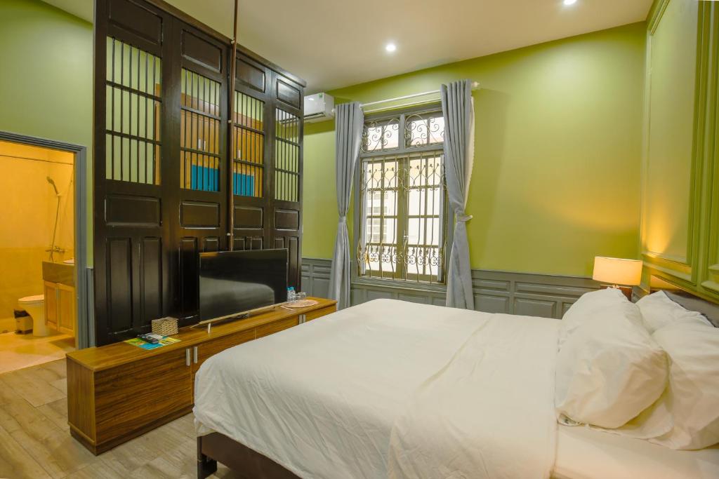 A bedroom with a television cabinet, curtained barred window, and bright green walls.