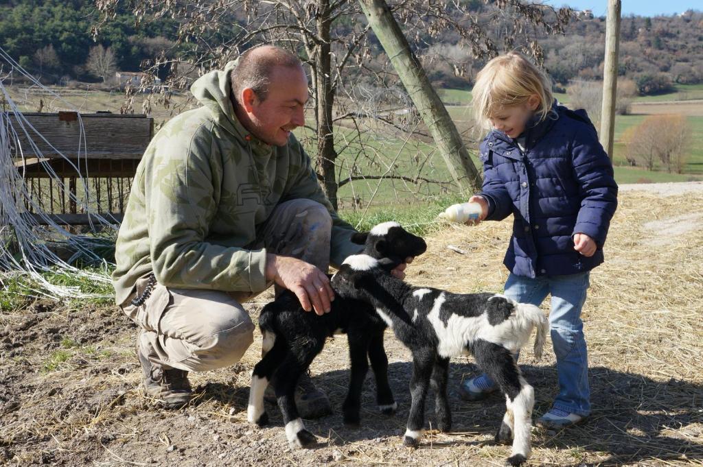 Un homme et une petite fille nourrissant deux bébés chèvres dans l'établissement Domaine du Bas Chalus, à Forcalquier