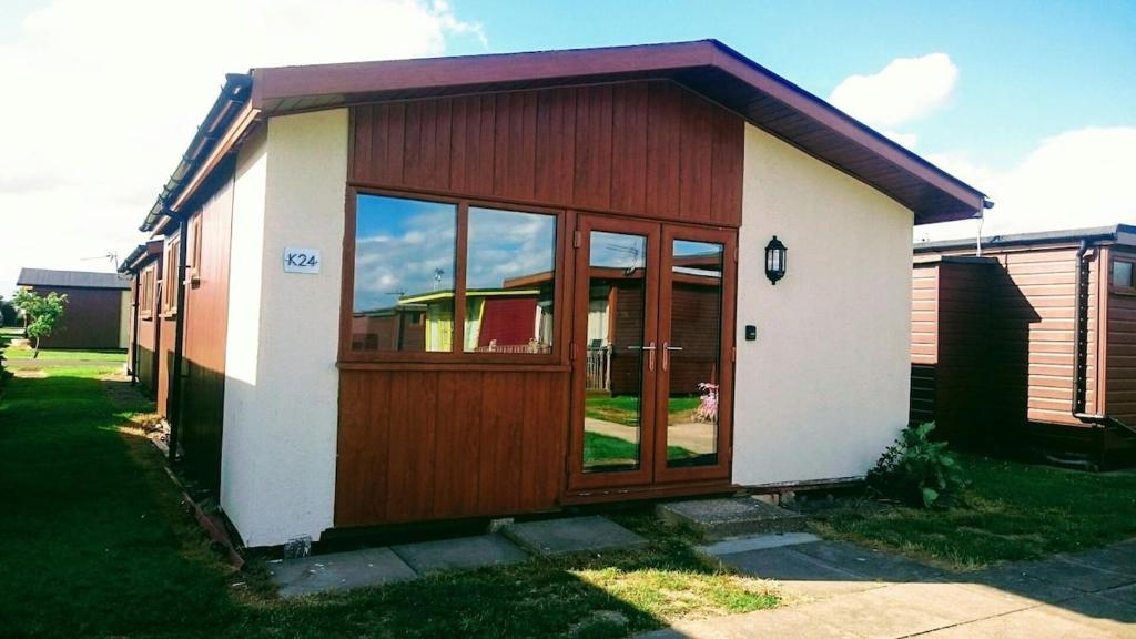 a small house with a wooden door in a yard at 6 Berth pet friendly Chalet in Mablethorpe