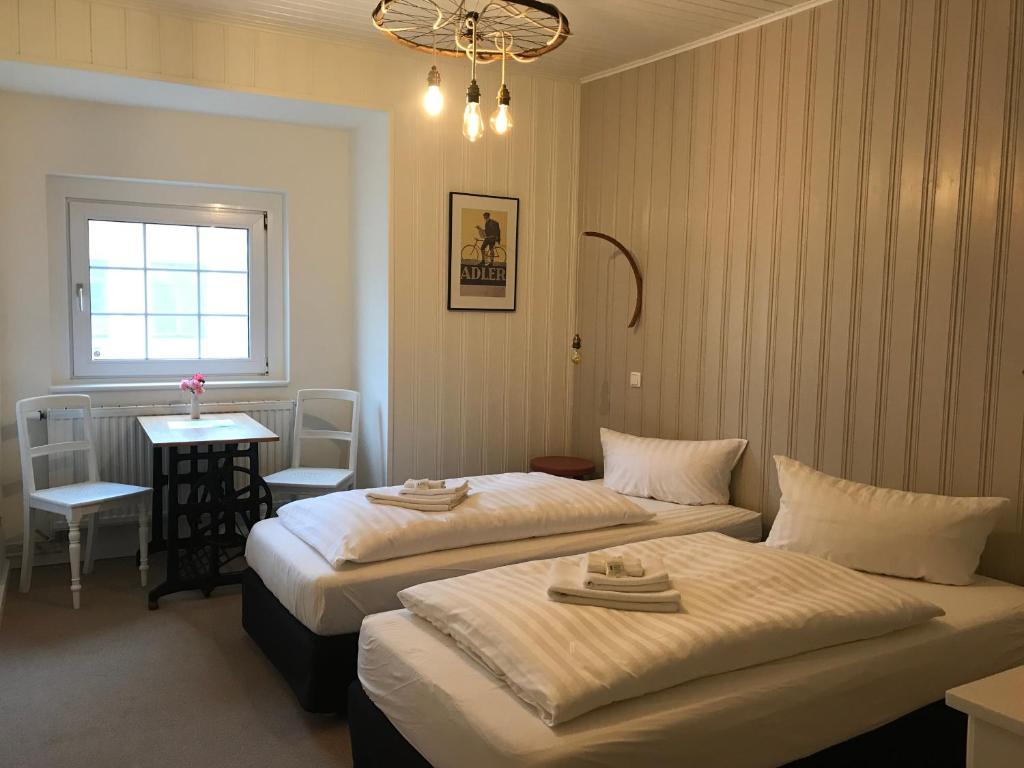una camera da letto con due letti, un tavolo e una finestra di Pension Central - Ihre Fahrradfreundliche Unterkunft in der Altstadt a Lutherstadt Wittenberg