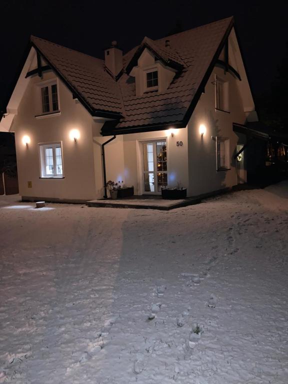 a house at night with snow in front of it at Agroturystyka u Sylwii in Majdan Sopocki