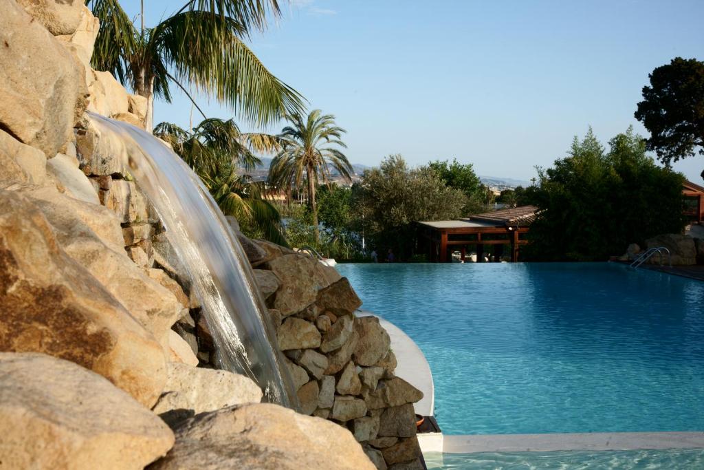 a swimming pool with a water slide next to a rock wall at Villa Morgana Resort and Spa in Torre Faro