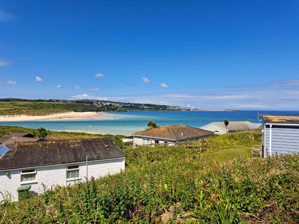 a group of houses on a hill next to a beach at B44 Sea Urchin, Riviere Towans in Hayle