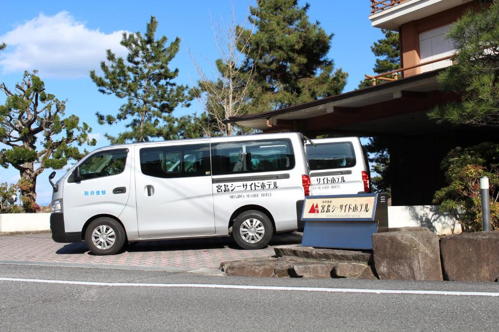 two white vans parked in a parking lot at Miyajima Seaside Hotel in Miyajima