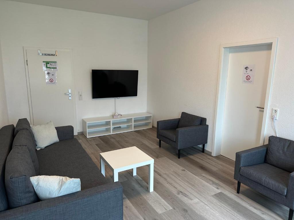 a living room with a couch and two chairs and a tv at Apart-Hotel Rheinischer Hof Dormagen in Dormagen