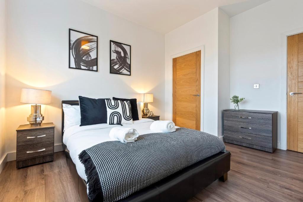 een slaapkamer met een groot bed met 2 nachtkastjes en 2 lampen bij Luxury 1-Bed Apartment in JQ, Sleeps 3, Parking & Netflix, Ideal for contractors in Birmingham