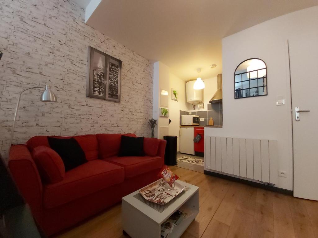 a living room with a red couch and a brick wall at Le Petit Saint-Georges, centre historique in Villefranche-de-Rouergue