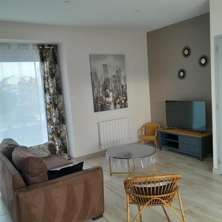 un salon avec un canapé, une table et une télévision dans l'établissement La Grange aux Abeilles 1, à Saint-Senier-sous-Avranches