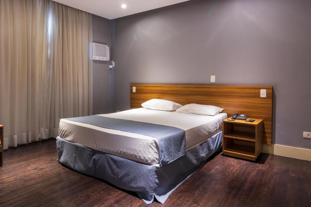 a bedroom with a large bed with a wooden headboard at Braston Augusta Hotel by Castelo Itaipava in Sao Paulo