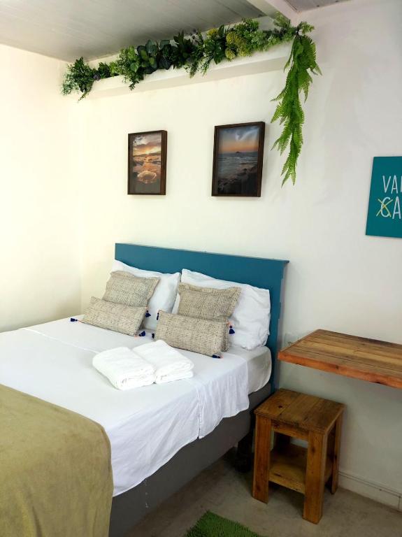 a bedroom with a bed with white sheets and a table at Suíte Colorida em Cabo Frio in Cabo Frio
