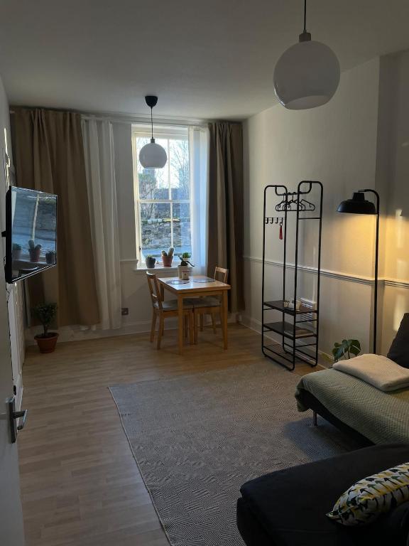 Una sala de estar con una mesa y un comedor. en Cozy flat in the heart of Leith, en Edimburgo