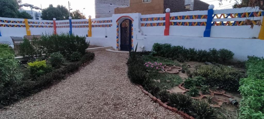 a garden with a white fence and a door at Kemet Guest House in Aswan