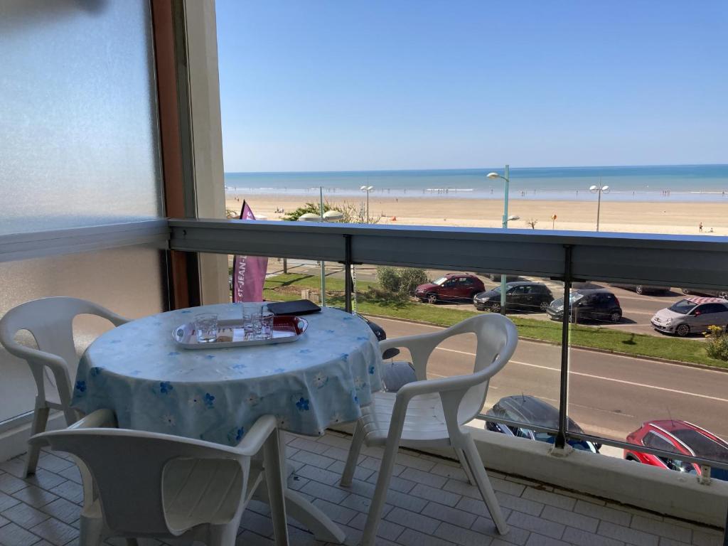 une table et des chaises sur un balcon avec vue sur la plage dans l'établissement La Perle Rose, à Saint-Jean-de-Monts