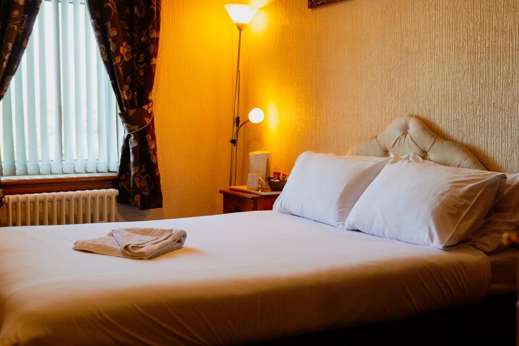een hotelkamer met een bed met een handdoek erop bij Station Hotel Larbert in Falkirk