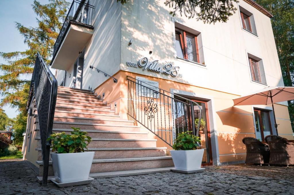 a staircase leading to a building with two potted plants at Apartamenty & SPA Villa 28 in Pobierowo