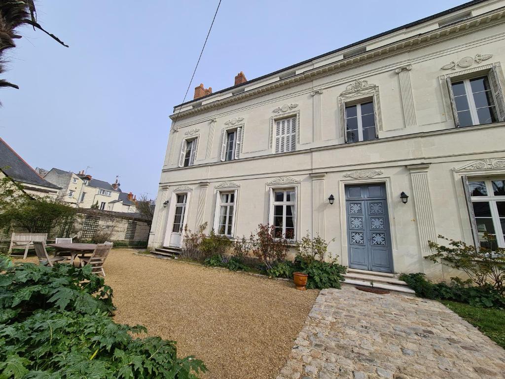 Une grande maison blanche avec une porte bleue dans l'établissement Léonard, à Saumur