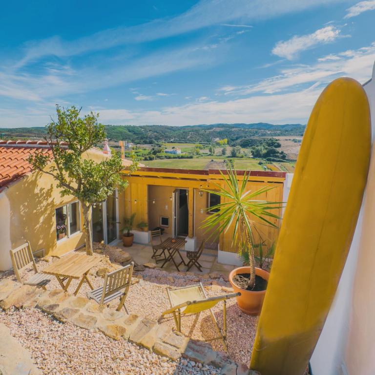 a large yellow surfboard standing next to a house at Casa de Malee in Aljezur