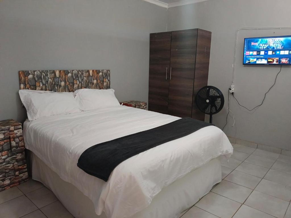 a bedroom with a large bed and a flat screen tv at Elim Pink House Accommodation in Elim