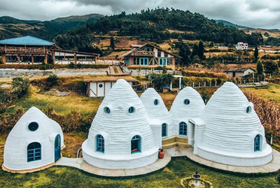 eine Gruppe weißer Häuser auf einem Feld in der Unterkunft Urku Wasi in Otavalo