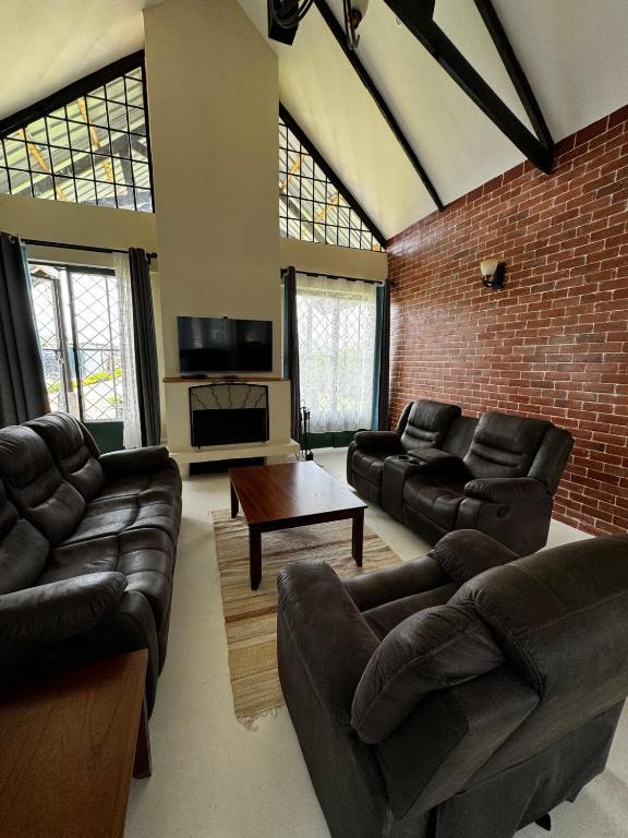 a living room with leather furniture and a brick wall at Cottage Ragati in Nanyuki