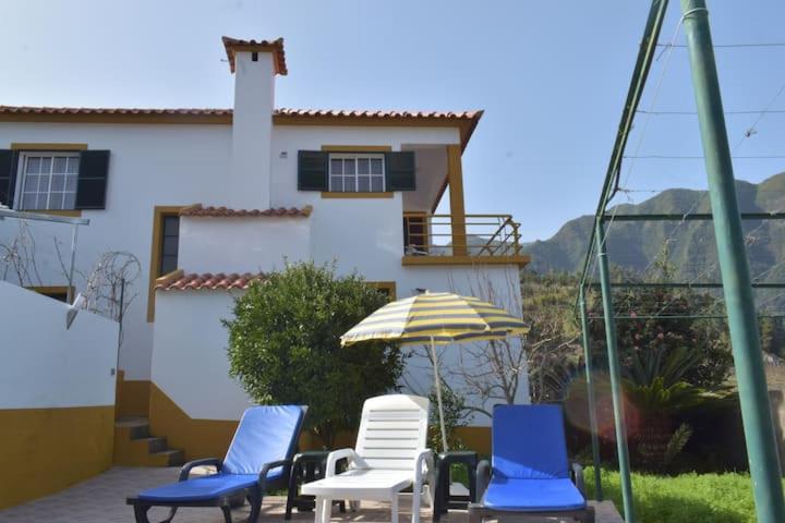 a group of chairs and an umbrella in front of a house at Quinta da Colina in São Vicente