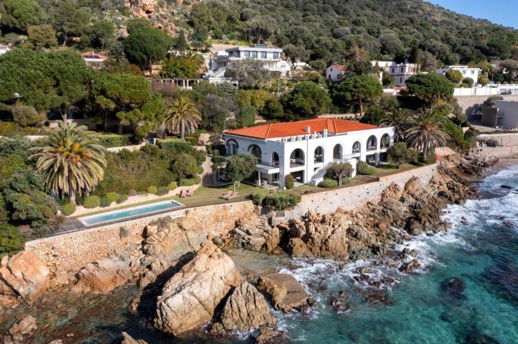 une maison sur une falaise à côté de l'eau dans l'établissement VILLA DOLCE VITA- 6 chambres, pieds dans l'eau, vue mer, piscine,, à Ajaccio