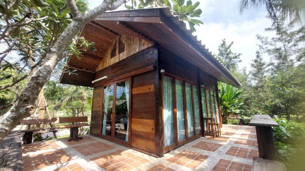 a small house with glass doors and a tree at Why Worry Homestay & Café in Ban Talat Khwai