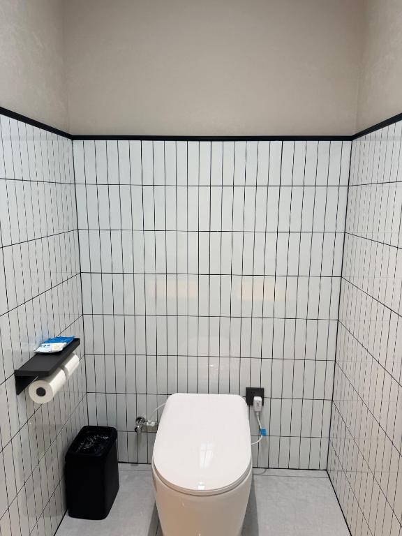 a bathroom with a toilet in a white tiled wall at Purple Stone High-End Designer Loft in Harbin