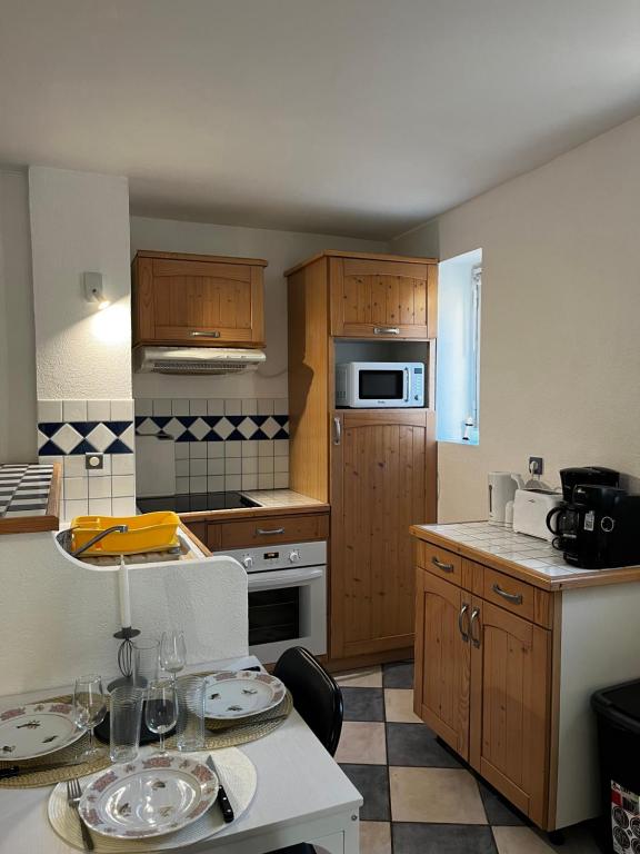 une cuisine avec des placards en bois et une table avec des assiettes. dans l'établissement Appartement T2 à 50 m de la plage, proche des commodités, à Canet