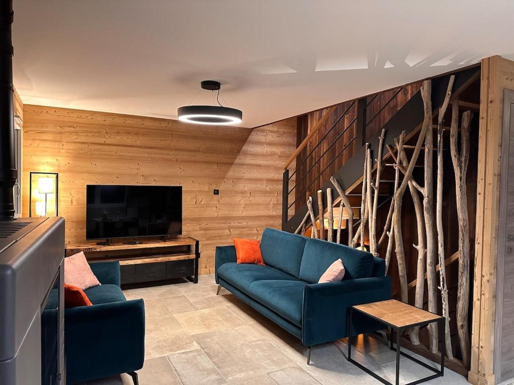 - un salon avec deux canapés bleus et une télévision dans l'établissement Chalet PLUME D'EAU - jacuzzi, piscine et pétanque, à Gerbépal