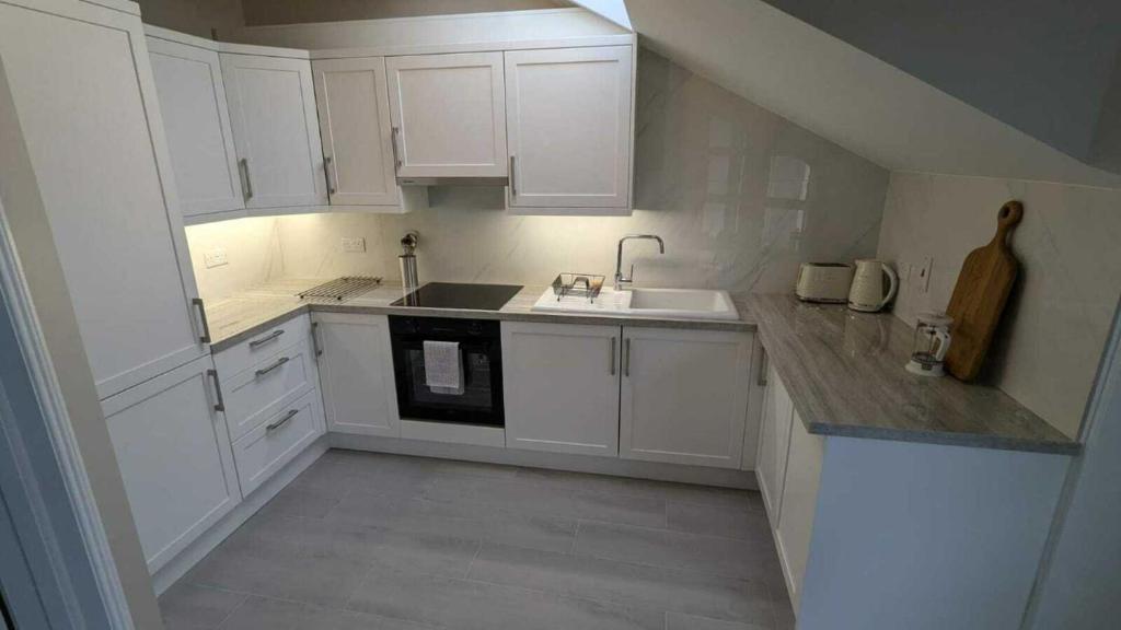 a white kitchen with white cabinets and a sink at Spacious & stylish upgraded 1BD Malahide Marina in Malahide