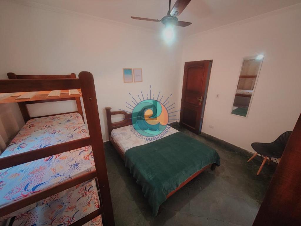 a bedroom with two bunk beds and a fan at Pousada Guaruondas in Guarujá