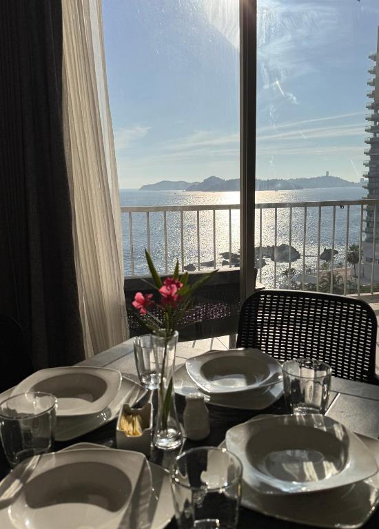 a table with plates and a view of the ocean at Suite Torres Gemelas Acapulco in Acapulco