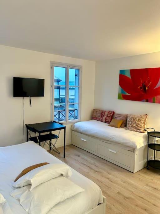 - une chambre avec 2 lits, une table et une télévision dans l'établissement Cosy studio Disney, à Serris